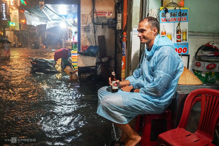 Khách Tây uống bia, ngắm đường phố Sài Gòn ngày mưa bão. Ảnh: Quỳnh Trần.